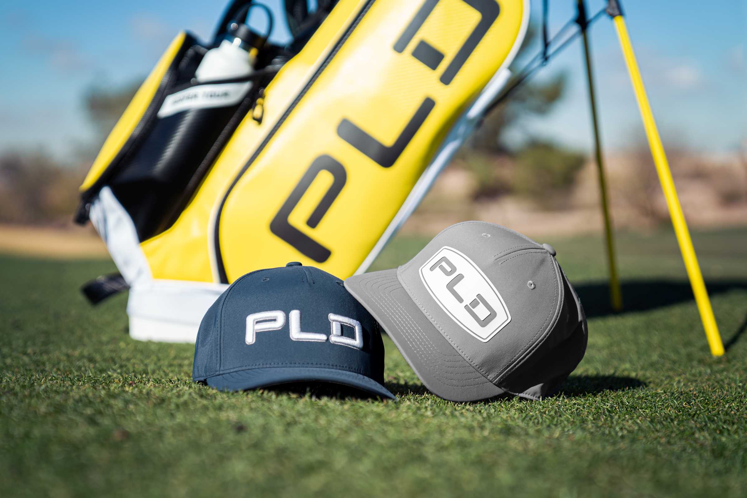 two PLD caps with a PLD golf bag in the background